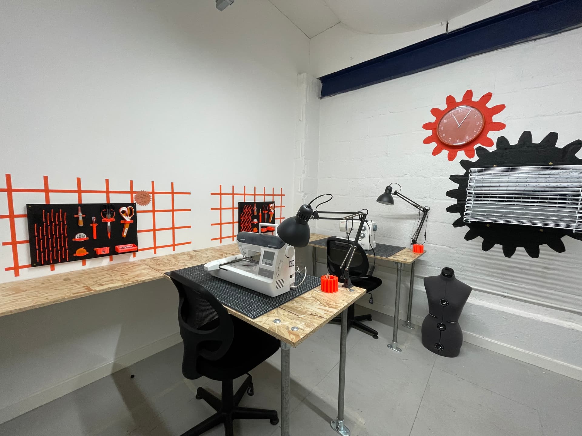 Two desks with sewing machines and a shadow-board of tools to the left of each of them.