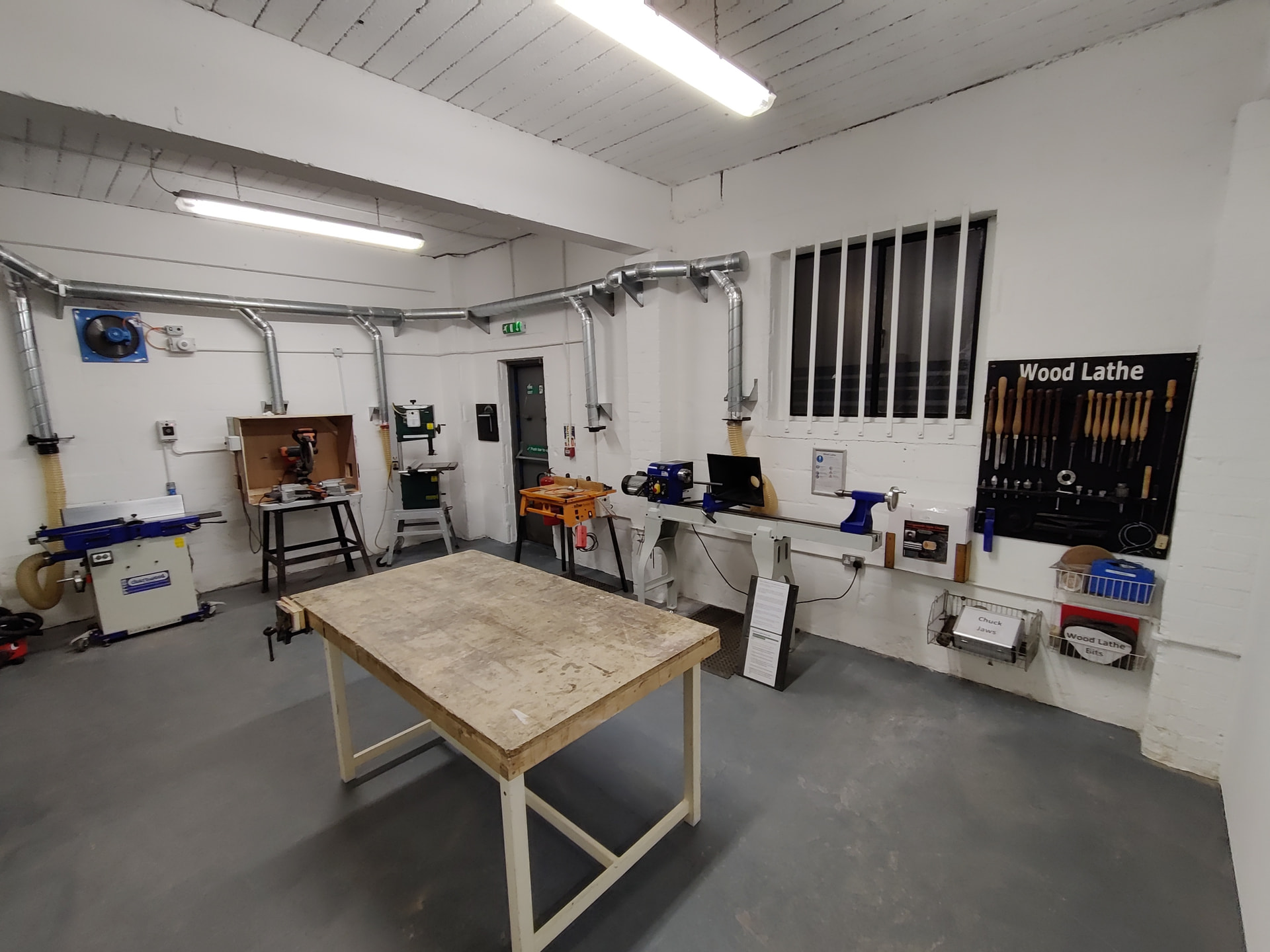 A woodworking area with a large workbench front and centre and larger floor-standing tools along the walls.